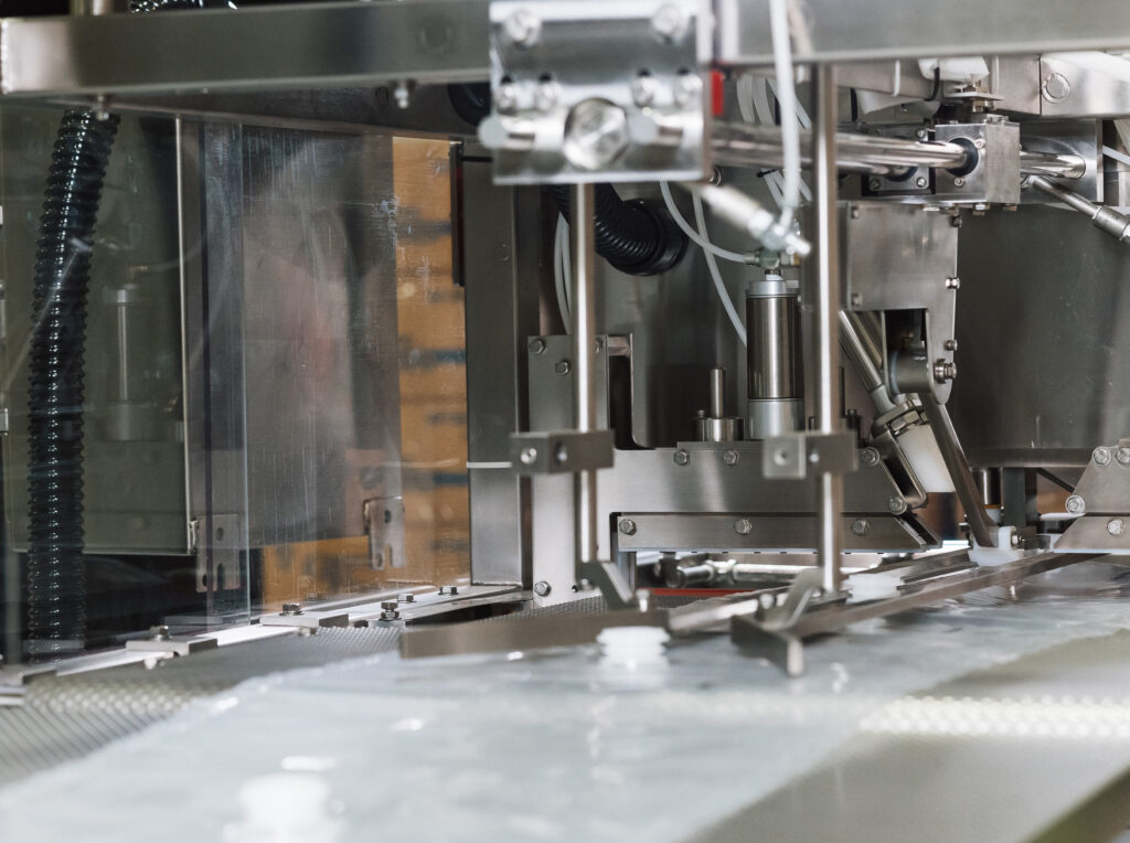 Bag-in-Box cap bags are going through the machine from a side view.