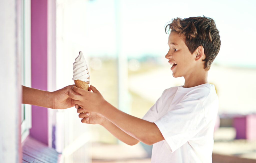 A young boy is receiving an ice cream cone and is smiling and grateful. Bag-in-Box solutions by General Films made it all possible.
